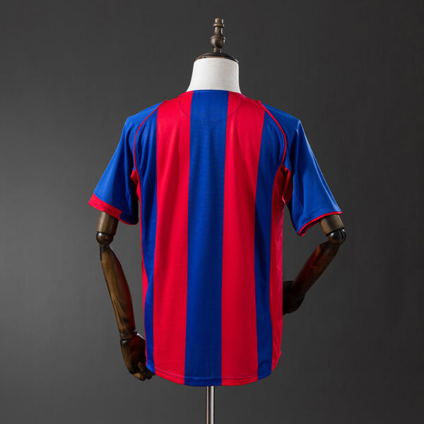 Back view of a blue and red vertical-striped soccer jersey on a mannequin.