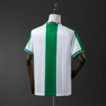 Back view of a white soccer jersey with a bold vertical green stripe down the center on a mannequin.