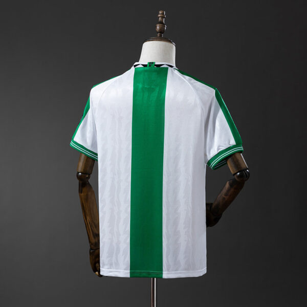 Back view of a white soccer jersey with a bold vertical green stripe down the center on a mannequin.