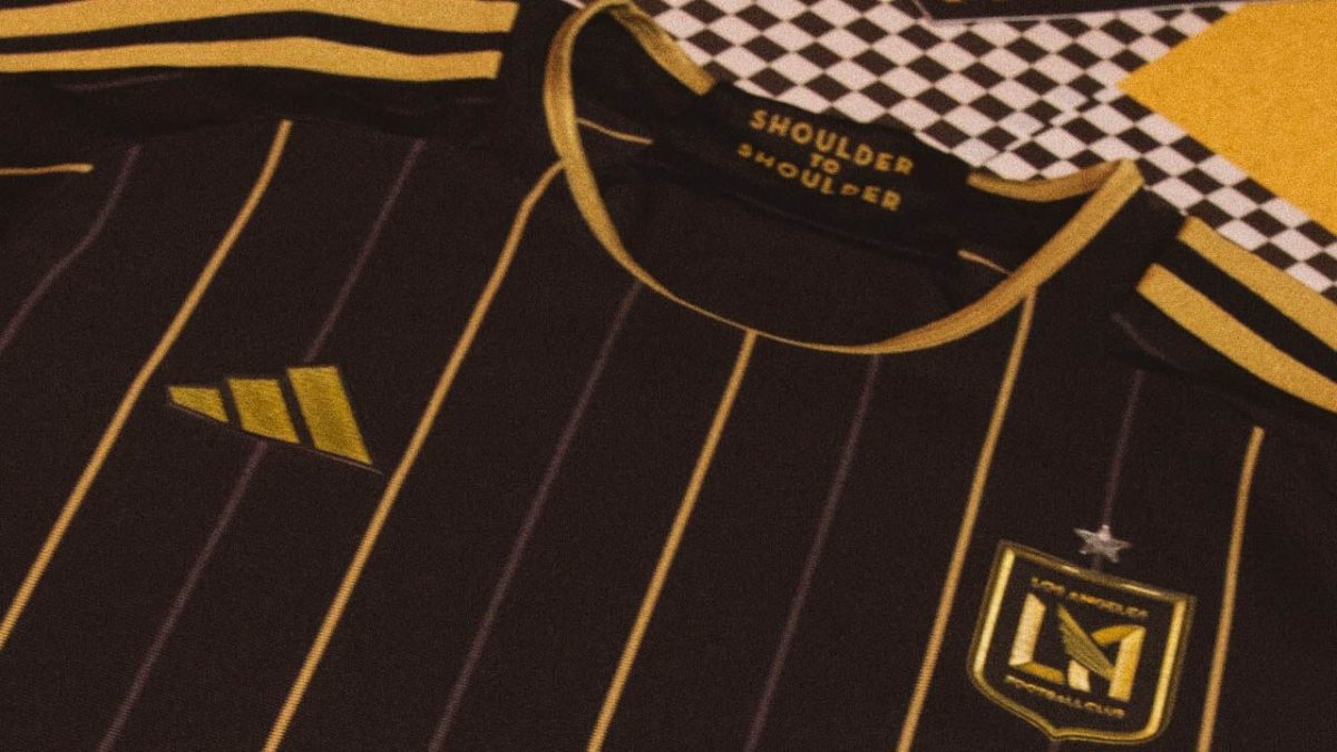 Black athletic jersey with vertical gold pinstripes, gold-trimmed collar, and an Adidas logo on the left chest; a team crest with a star is on the right chest.