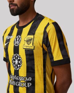 Close-up of a person wearing a yellow and black striped sports jersey with team crest and sponsor patches visible on the chest.