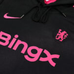 Close-up of a black hoodie with bright pink branding: large 'bingx' text, a circular pink lion crest patch, and a pink Nike swoosh visible on the chest area.