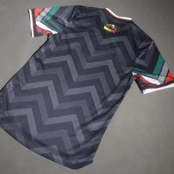 Dark athletic jersey with a large zigzag pattern and multicolor striped sleeves laid flat on a gray surface.