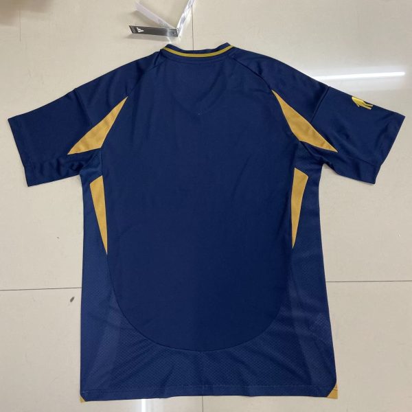 Back view of a blue athletic jersey with gold triangular panels along the sides and yellow trim at the collar.