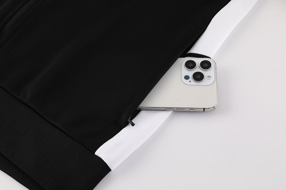 3b9f2630 | UAE SPORT STORE Black jacket with a white side panel, a smartphone partially poking out of a pocket near the hem with the camera module visible