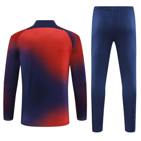 Back view of a gradient red-to-navy long-sleeve athletic top matched with solid blue jogger pants, a two-piece tracksuit.