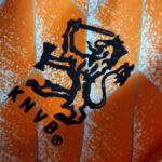 Black silhouette of a knight holding a sword above the letters KNVB on an orange geometric background.