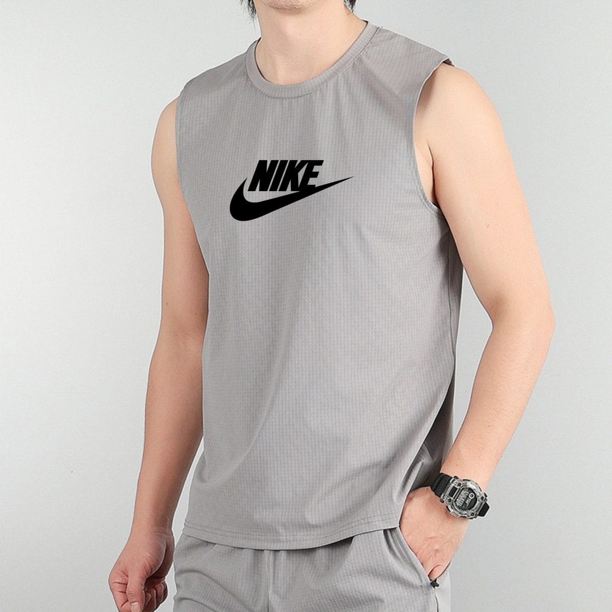Person wearing a gray sleeveless Nike tank top with a black Nike swoosh logo on the chest.