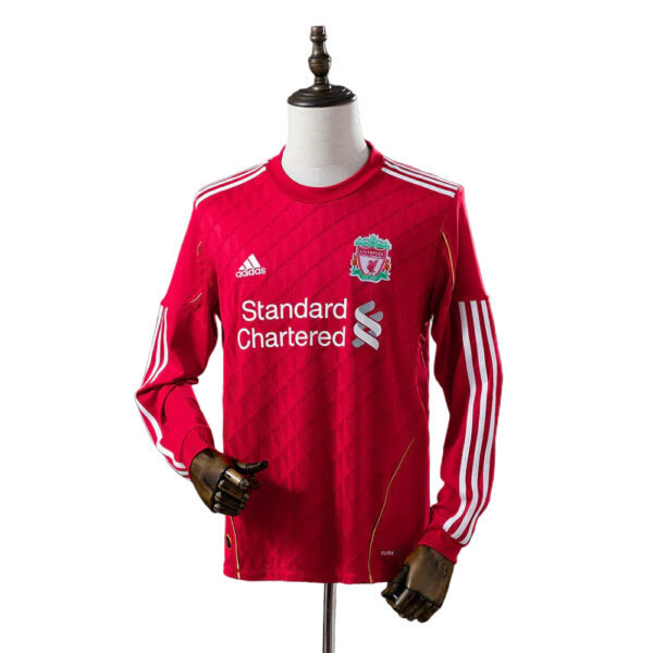 Red Liverpool FC training jersey on a mannequin, featuring the Standard Chartered sponsor and Adidas logo with white stripes on the shoulders and sleeves.