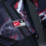 Close-up of a patterned athletic jacket with a Nike patch and size 'M' label on the hem area, dark blue and red tones.