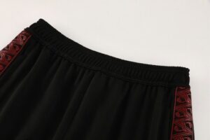 Black athletic shorts with an elastic waistband and red geometric side stripes on each leg.