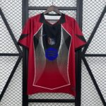 Red sports jersey on a wooden hanger, with a black center panel and white diagonal lines, against a metal lattice backdrop.