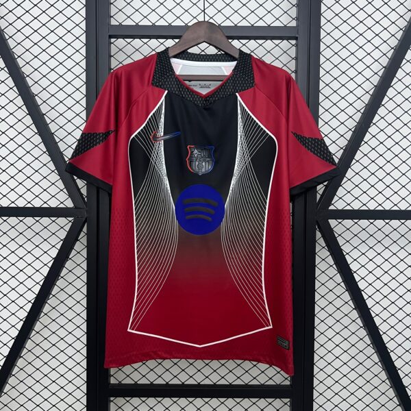 Red sports jersey on a wooden hanger, with a black center panel and white diagonal lines, against a metal lattice backdrop.