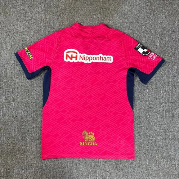 Back of a bright pink soccer jersey with blue side panels, featuring the Nipponham sponsor logo and a gold Singha emblem at the hem.