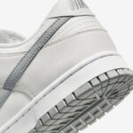 Close-up of a white leather sneaker heel with a gray side stripe and stitched details.