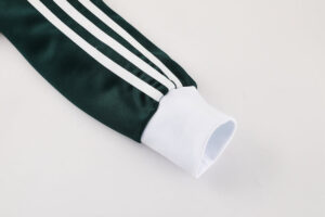 Close-up of a dark green athletic jacket sleeve with white stripes and a white cuff.