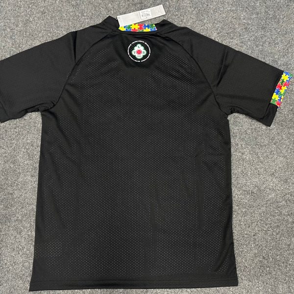 Black polo shirt with rainbow puzzle-piece trim on the collar and sleeve ends, and a circular emblem on the upper back.