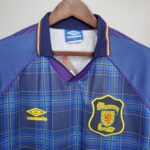 Blue plaid soccer jersey on a hanger, showing Umbro tag and Scottish Football Association crest with purple and yellow trim.