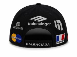 Back view of a black cap with embroidered Balenciaga logos and patches, including Mastercard circles and the French flag, and an adjustable strap with Balenciaga text.