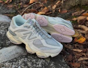 Gray New Balance running shoes resting on a stone edge with brown autumn leaves around them around the outdoor setting.