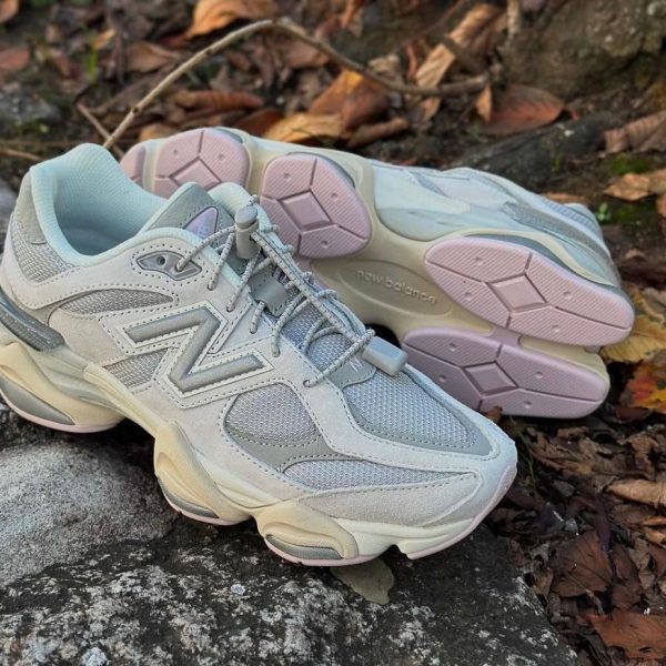 Gray New Balance running shoes resting on a stone edge with brown autumn leaves around them around the outdoor setting.