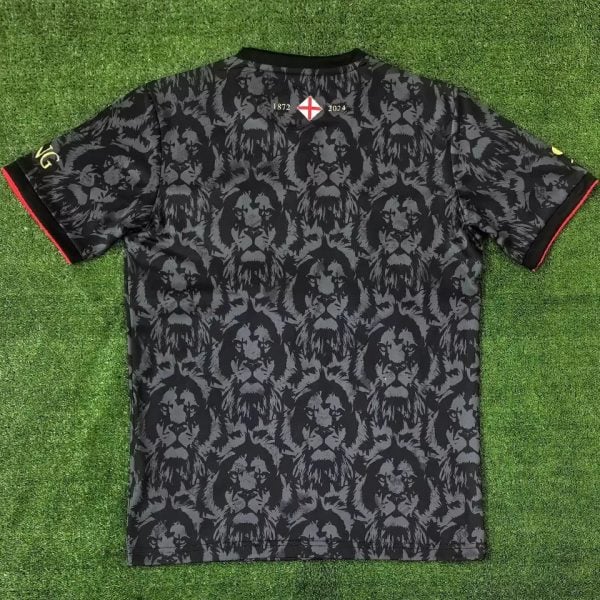 Back view of a black jersey with a repeating lion motif; near the collar note '1872 2024' and a small white shield with a red cross.