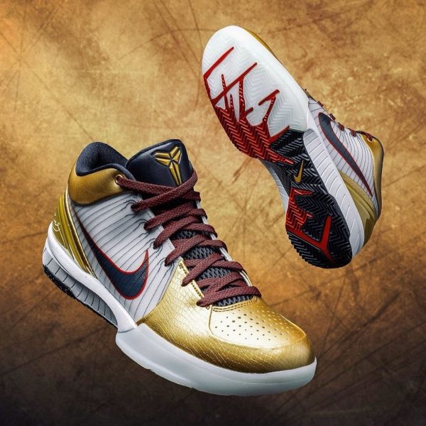 Gold and white basketball sneakers with maroon laces, navy accents, and a textured sole set against a brown, grunge background.