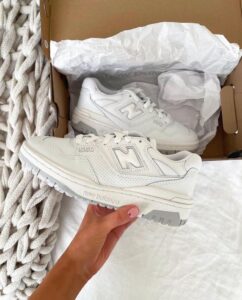 Pair of white New Balance 550 sneakers in a shoebox with tissue paper.