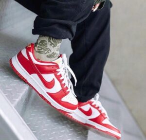3ff3dcbe-acb6-4747-a685-4d932582fe3d_f0d46f01-0c5d-4295-8bcf-3b8eb04e32ec | UAE SPORT STORE Close-up of red and white sneakers on a person stepping down a metal staircase, camo socks peeking out.