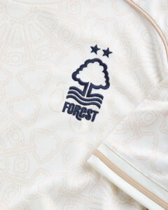 White polo shirt with navy embroidered Forest logo (tree with waves) and two stars.