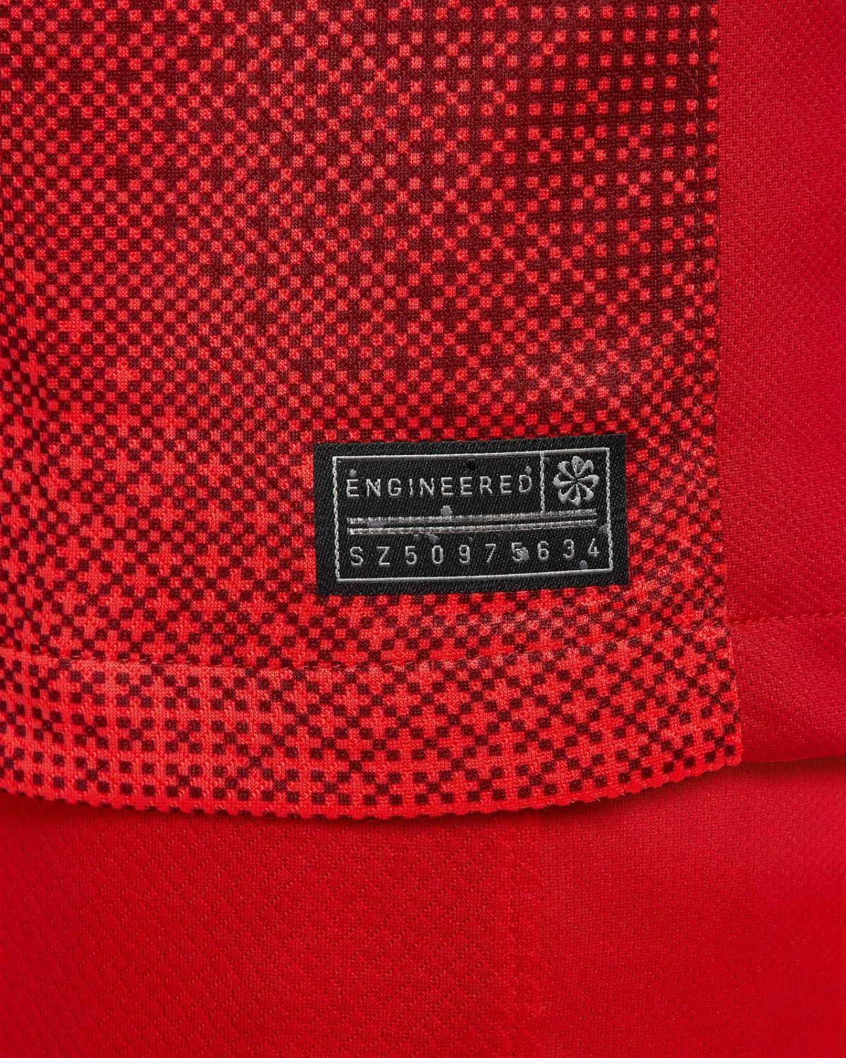Close-up of red patterned fabric with a black tag reading 'ENGINEERED' and the serial S750975634.