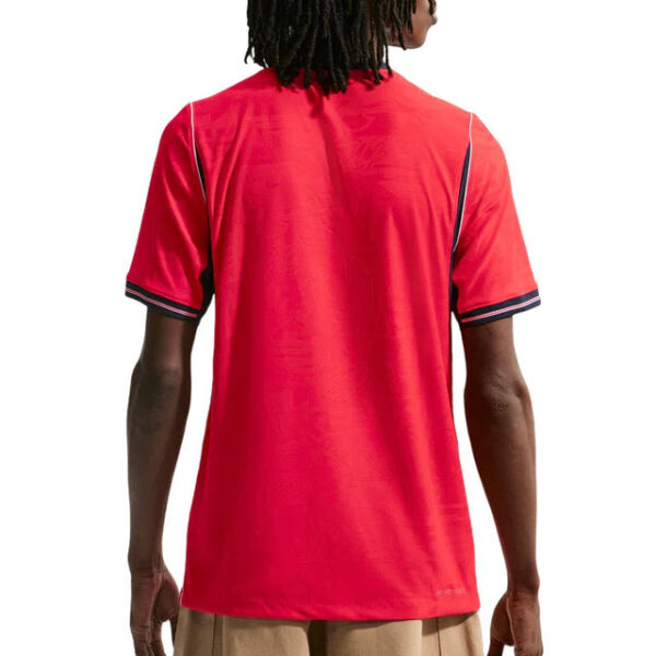 Back view of a person wearing a bright red polo shirt with dark trim on the sleeves, standing against a white background.