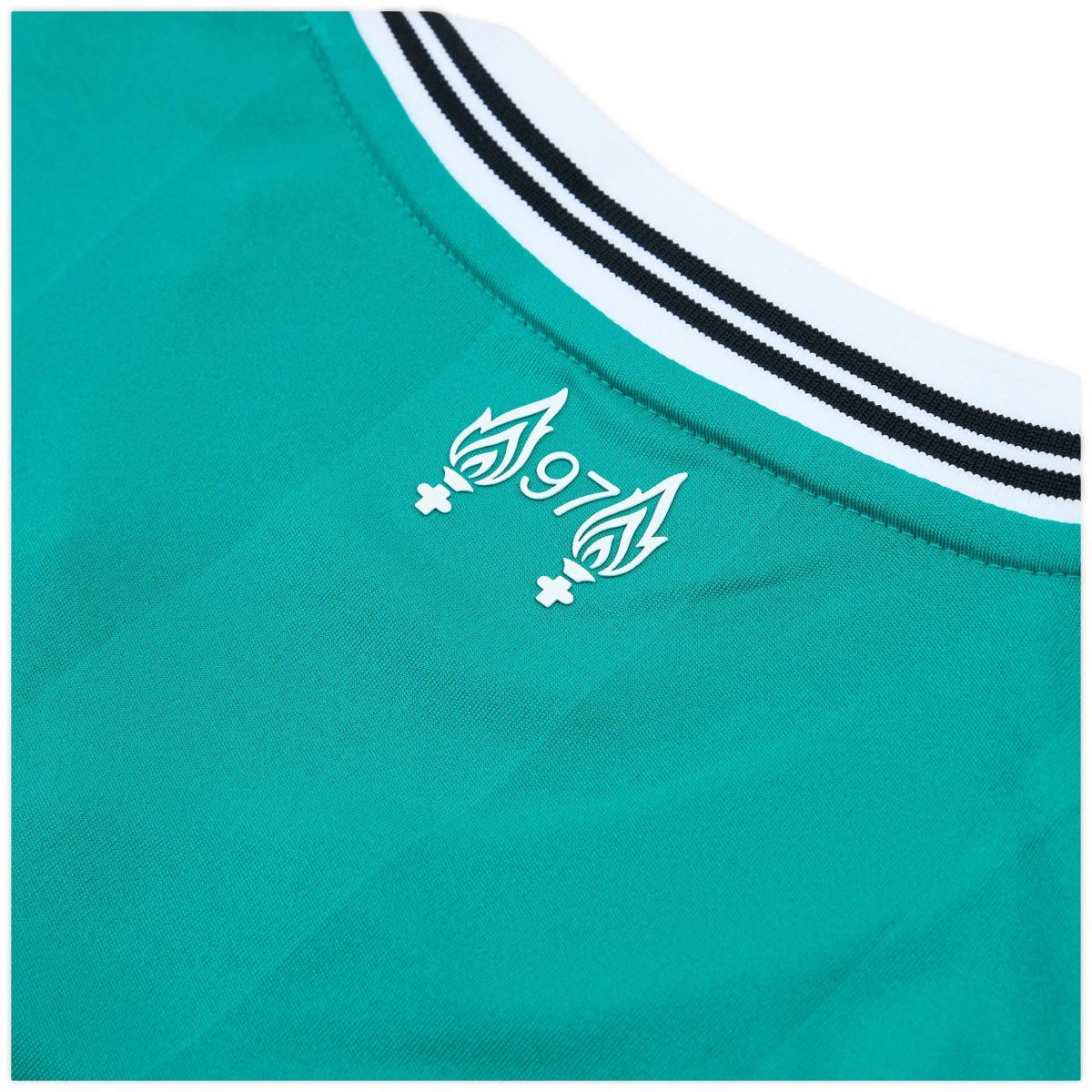 Partial close-up of a teal sneaker, showing teal fabric and a white midsole with two black stripes along the edge.