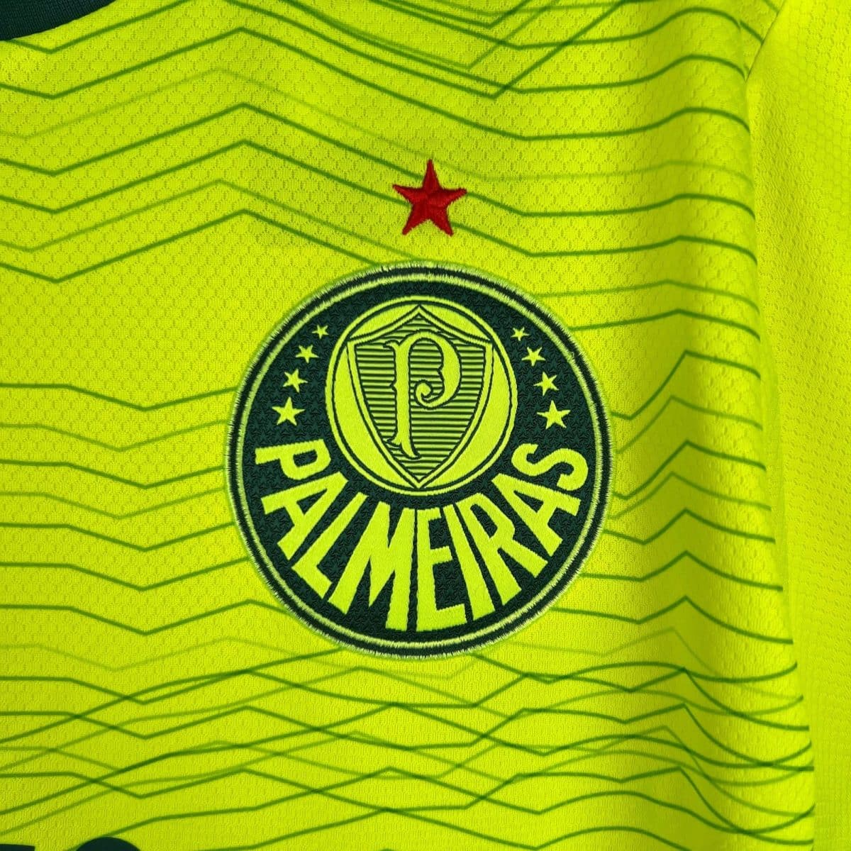 Close-up of neon yellow high-visibility fabric with a red star and a circular emblem nearby.