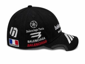 Black Balenciaga cap with multiple embroidered logos (Balenciaga Paris, French flag patch) and a curved brim.