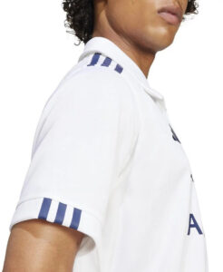 43af04837154844ba2fad2144896d8db | UAE SPORT STORE Side view of a person in a white polo shirt featuring blue stripes on the sleeve cuffs and shoulder.