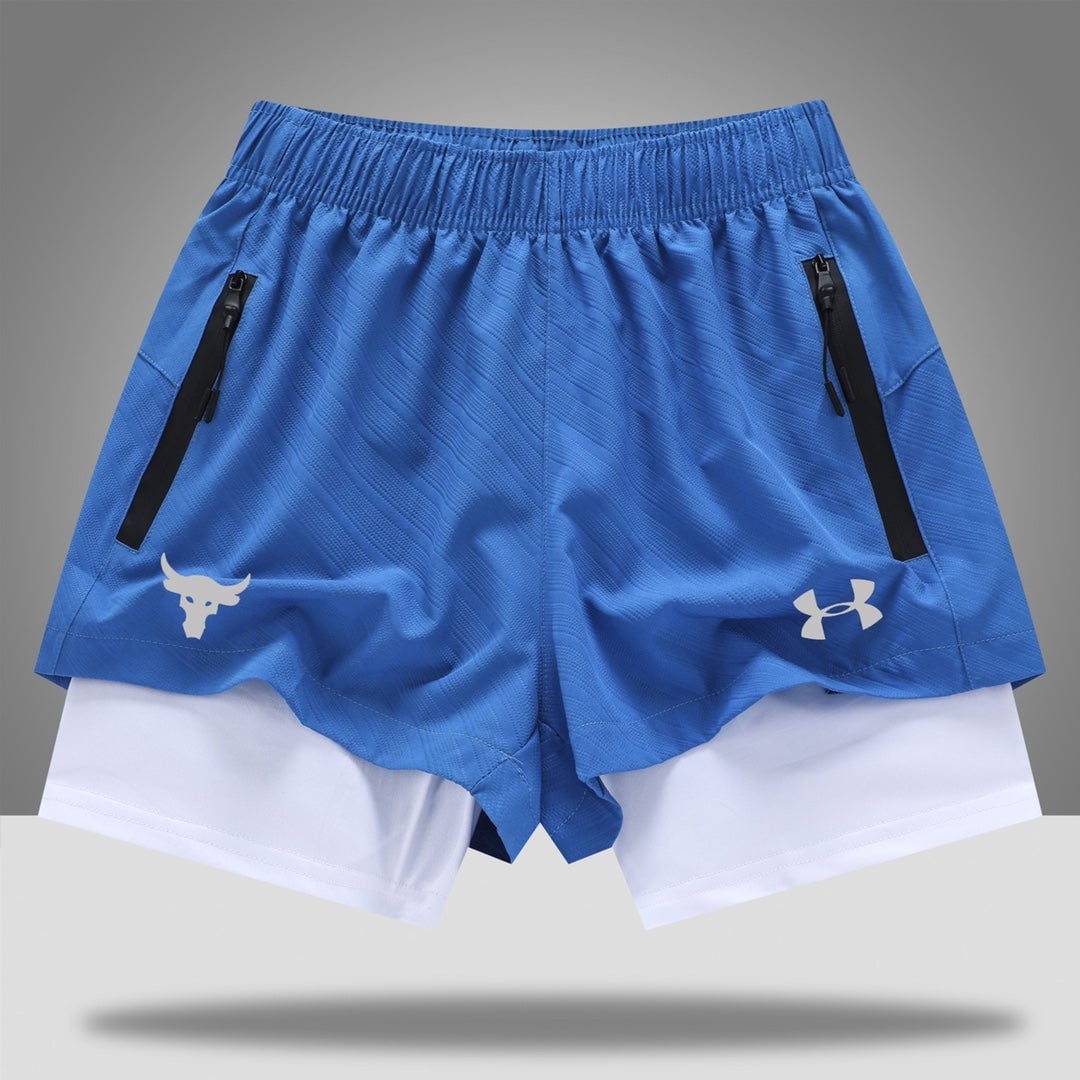 4430c703 | UAE SPORT STORE Blue athletic shorts with zippered side pockets and a white inner layer peeking at the bottom, featuring a white logo on the left and the Under Armour logo on the right thigh side.