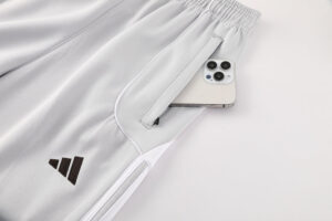 Light gray athletic pants with an Adidas logo and a phone tucked into a side pocket near the hip area