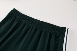 Dark green athletic pants with an elastic waistband and zippered side pockets, featuring white side stripes.