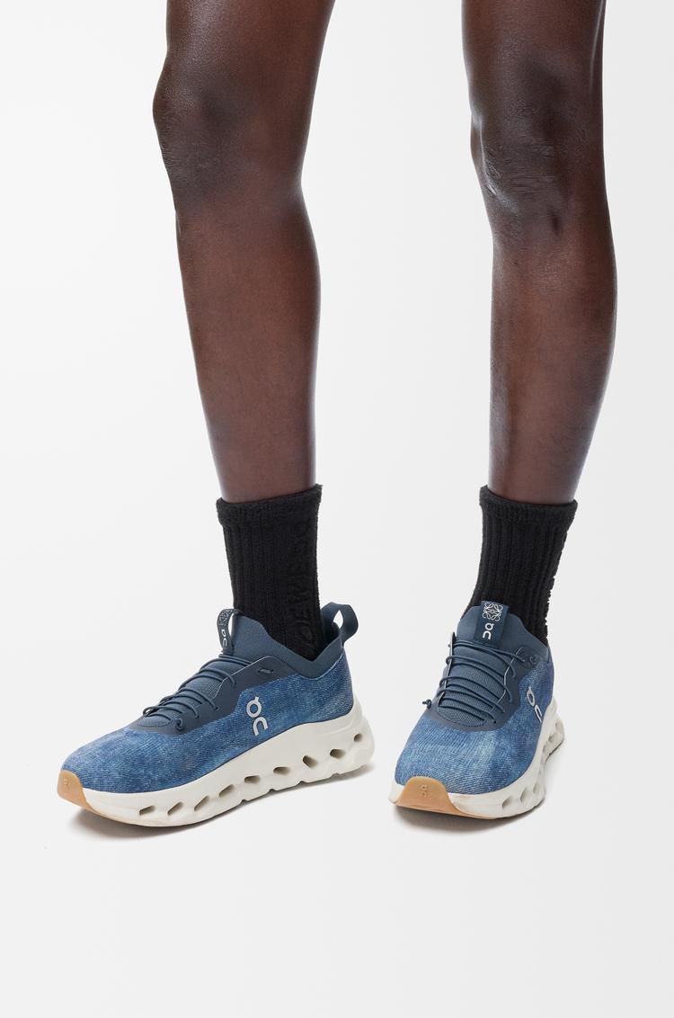 455e80d7-ac37-41ee-8dc7-33b0847921e2 | UAE SPORT STORE Blue athletic sneakers with a chunky white sole, worn with black socks against a white background.