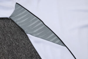 Close-up of a white garment with a grey patterned sleeve lining visible along a black seam.