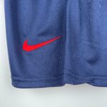 Close-up of blue fabric with a red Nike swoosh embroidered along the seam.