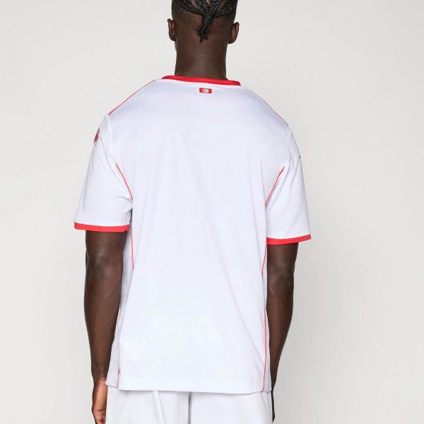 Back view of a person wearing a white athletic jersey with red trim, small flag patch on the upper back.