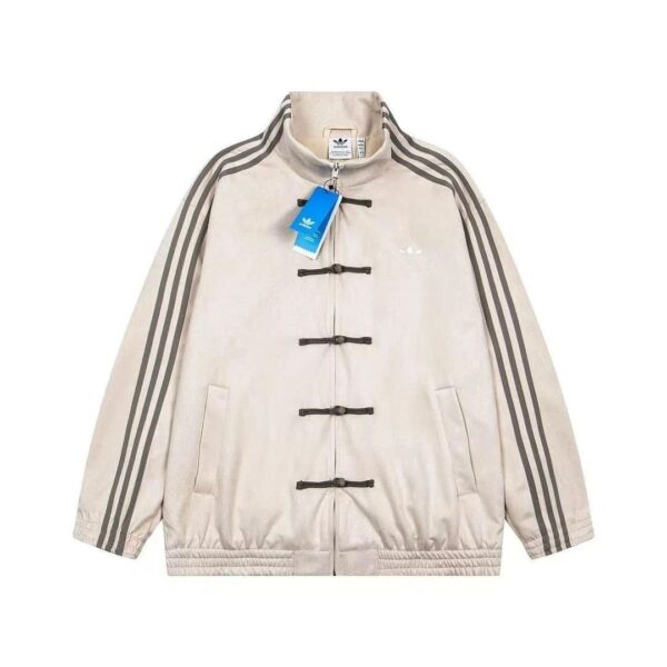 Beige Adidas track jacket with toggle closures, three black stripes along the sleeves, small chest logo, and blue tag attached.