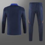 Back view of a navy blue athletic long-sleeve top and matching jogger pants set, with orange knee accents on the pants.