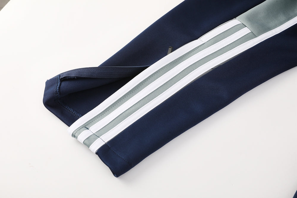 46c0716b | UAE SPORT STORE Navy track pants leg with white and gray stripes running down the side and a light gray cuff detail near the ankle.