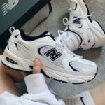 46e45a2b-f8a4-4901-a095-d98119c64a75 | UAE SPORT STORE White New Balance 530 sneakers held in hand, showing mesh panels, white laces, and the NB logo.