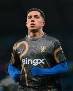 474562575_18492982957021107_8919439177722111598_n | UAE SPORT STORE Soccer player in a dark geometric-pattern jersey with gold crest, blue sleeves, and BingX logo, focused expression.