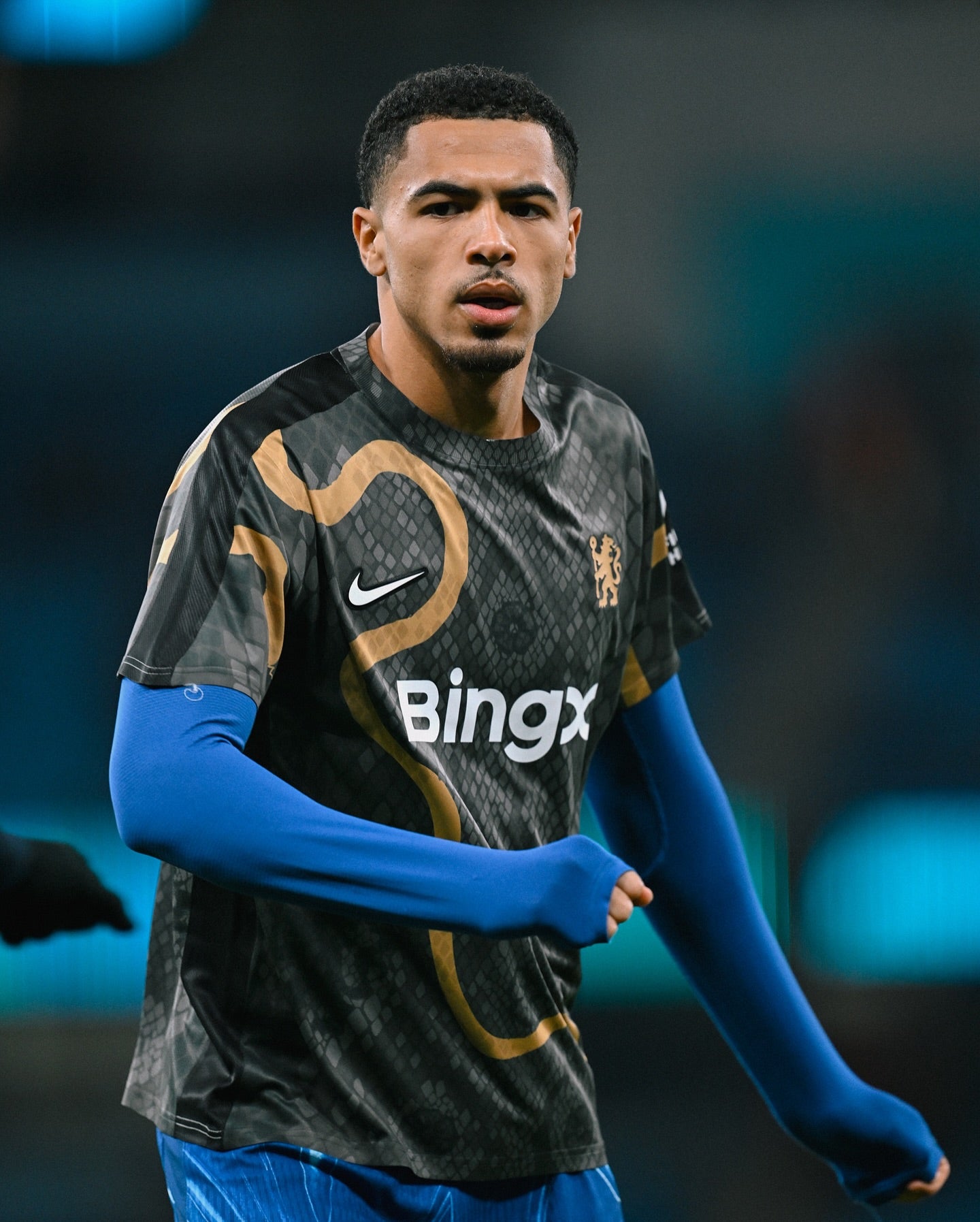 474999646_18492982975021107_6644316567304939709_n | UAE SPORT STORE Male footballer in a black patterned jersey with blue undershirt, running on the field.