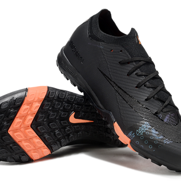Pair of black Nike Mercurial soccer cleats with orange outsole, shown in an angled side view.